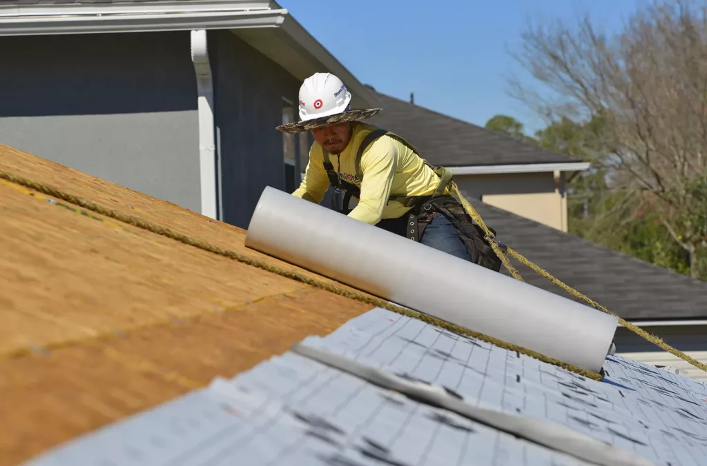 A StormForce team member rolling out underlayment on a new roof project in Jacksonville.