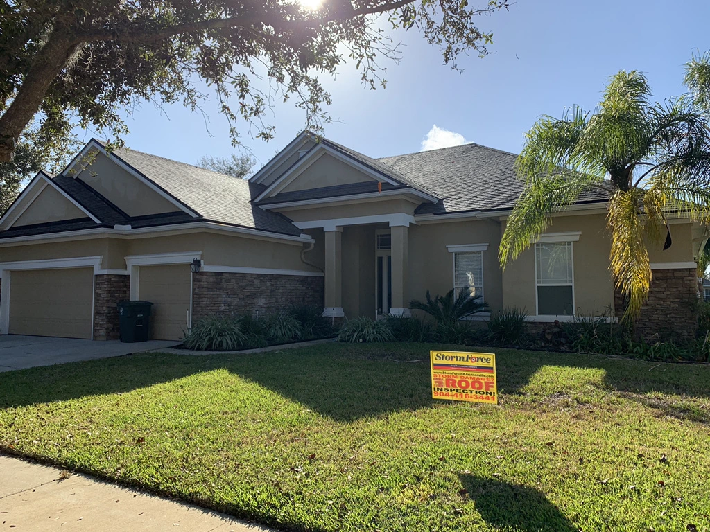 A home in the Jacksonville area with a new asphalt shingle roof with a StormForce Roofing yard sign.