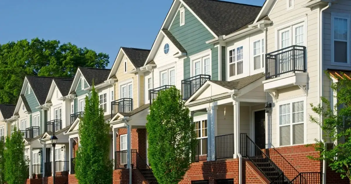 A row of multi-family townhouses with varying rooflines, featuring gable and hip roofs with asphalt shingles, reflecting a suburban residential roofing style. 