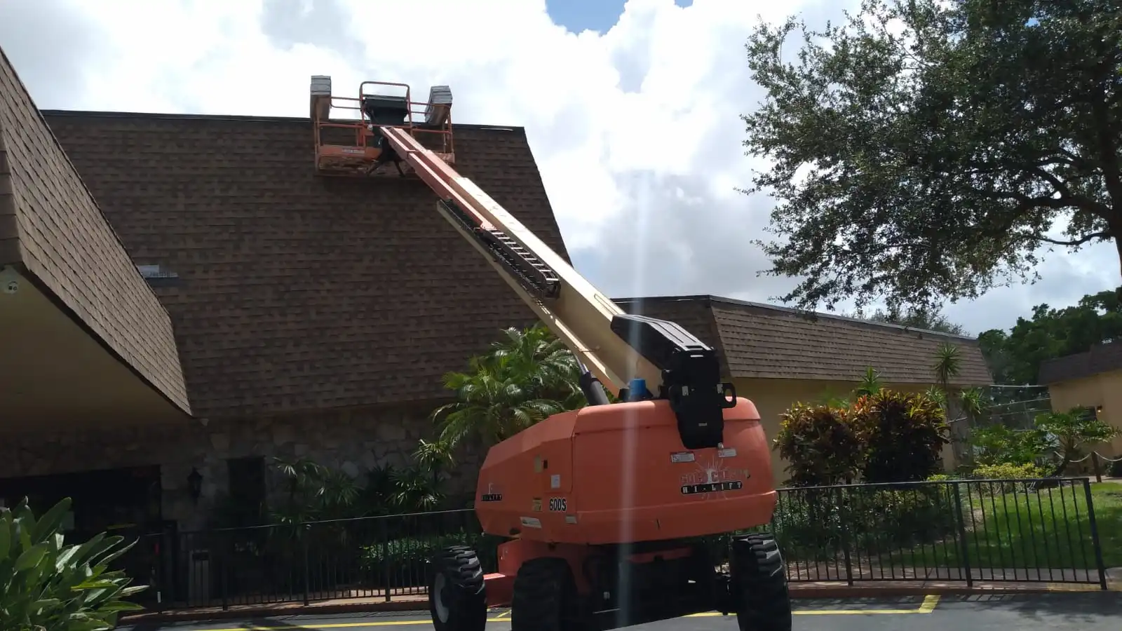 A telescopic lift conveying roofing materials to the roof of a building, with a focus on industrial roofing maintenance or installation.